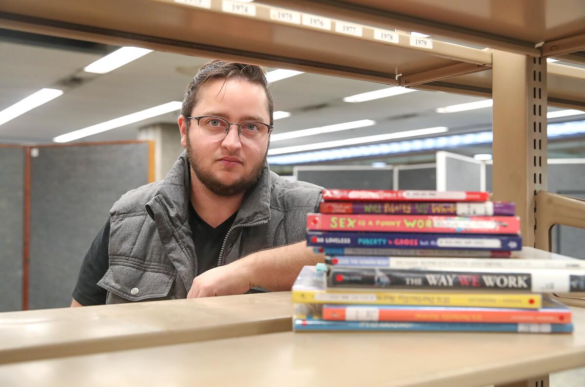 Advocate Kane Durham with some of the books in question at the Huntington Beach Public Library on Tuesday.