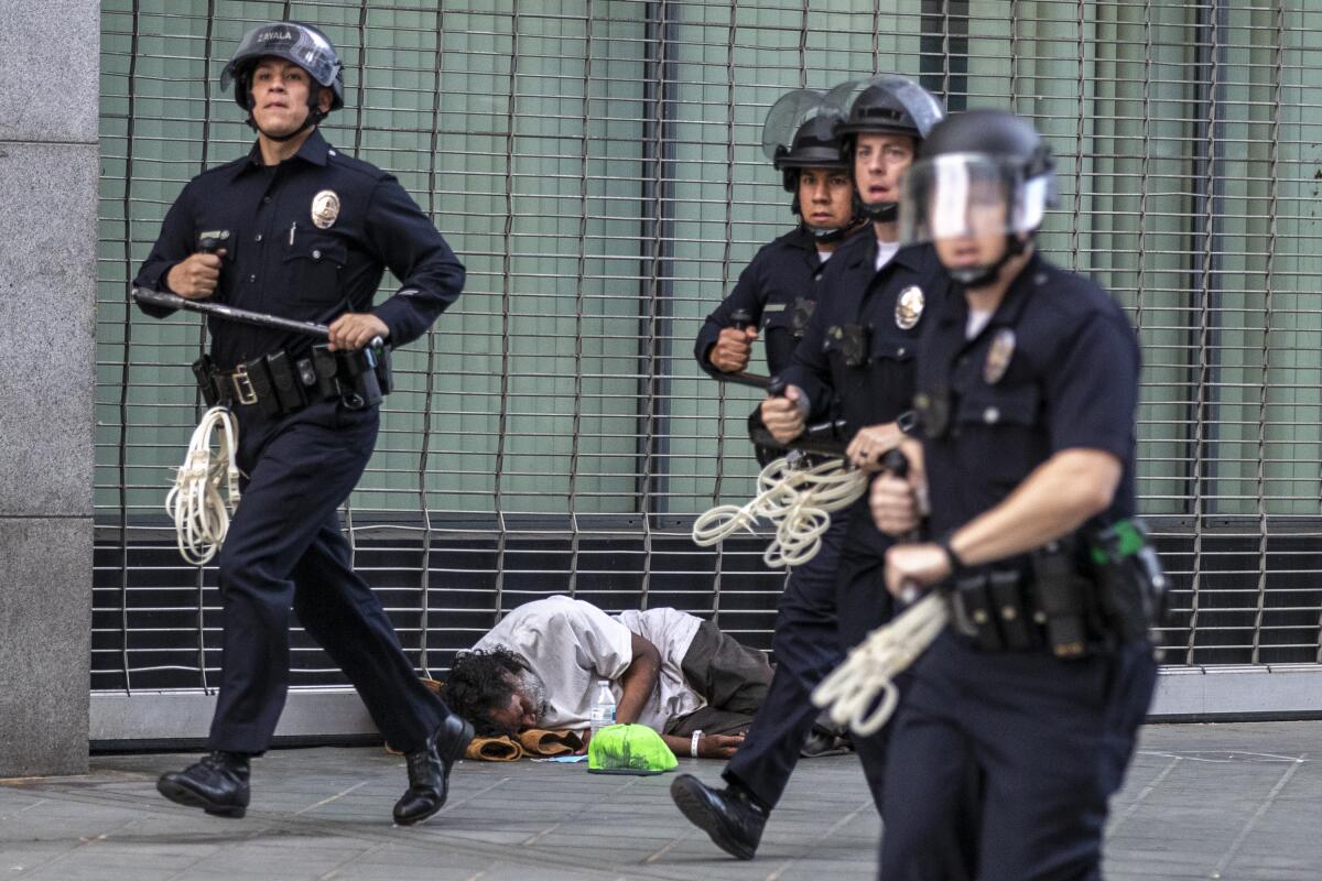 Los Angeles police officers rush to arrest dozens of protesters who were violating curfew laws on Broadway on Tuesday. 