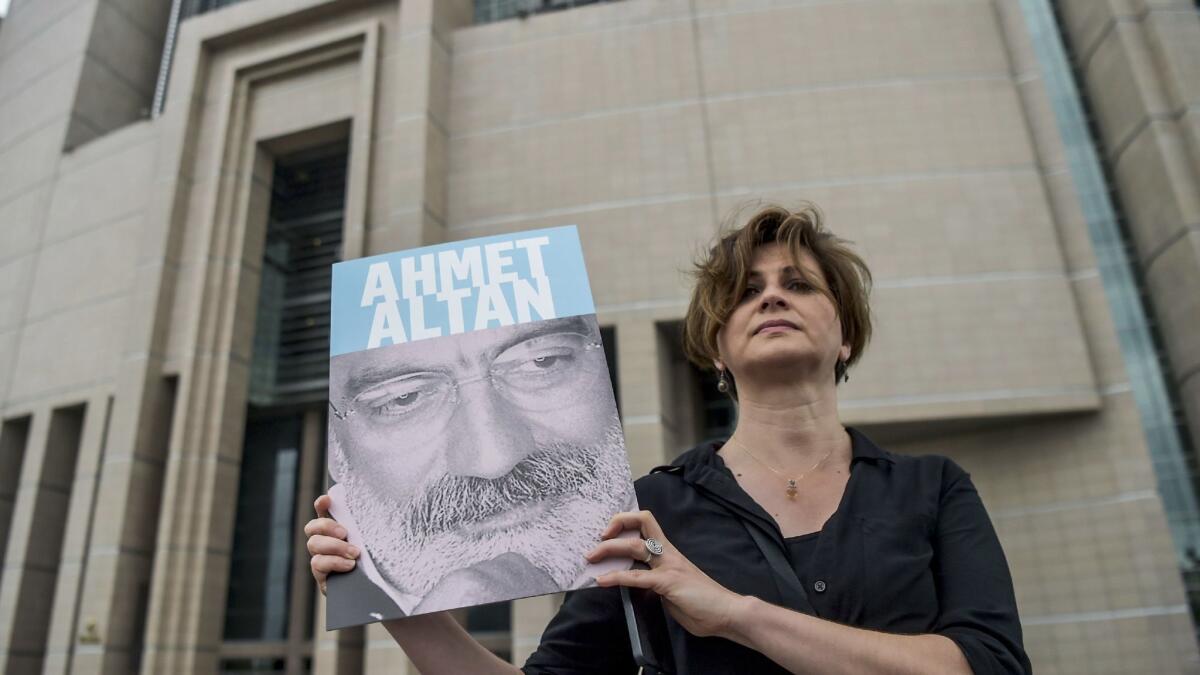 A journalist poses with a portrait of Turkish journalist Ahmet Altan on June 19, 2017 in front of the Istanbul courthouse, where his trial is to take place.