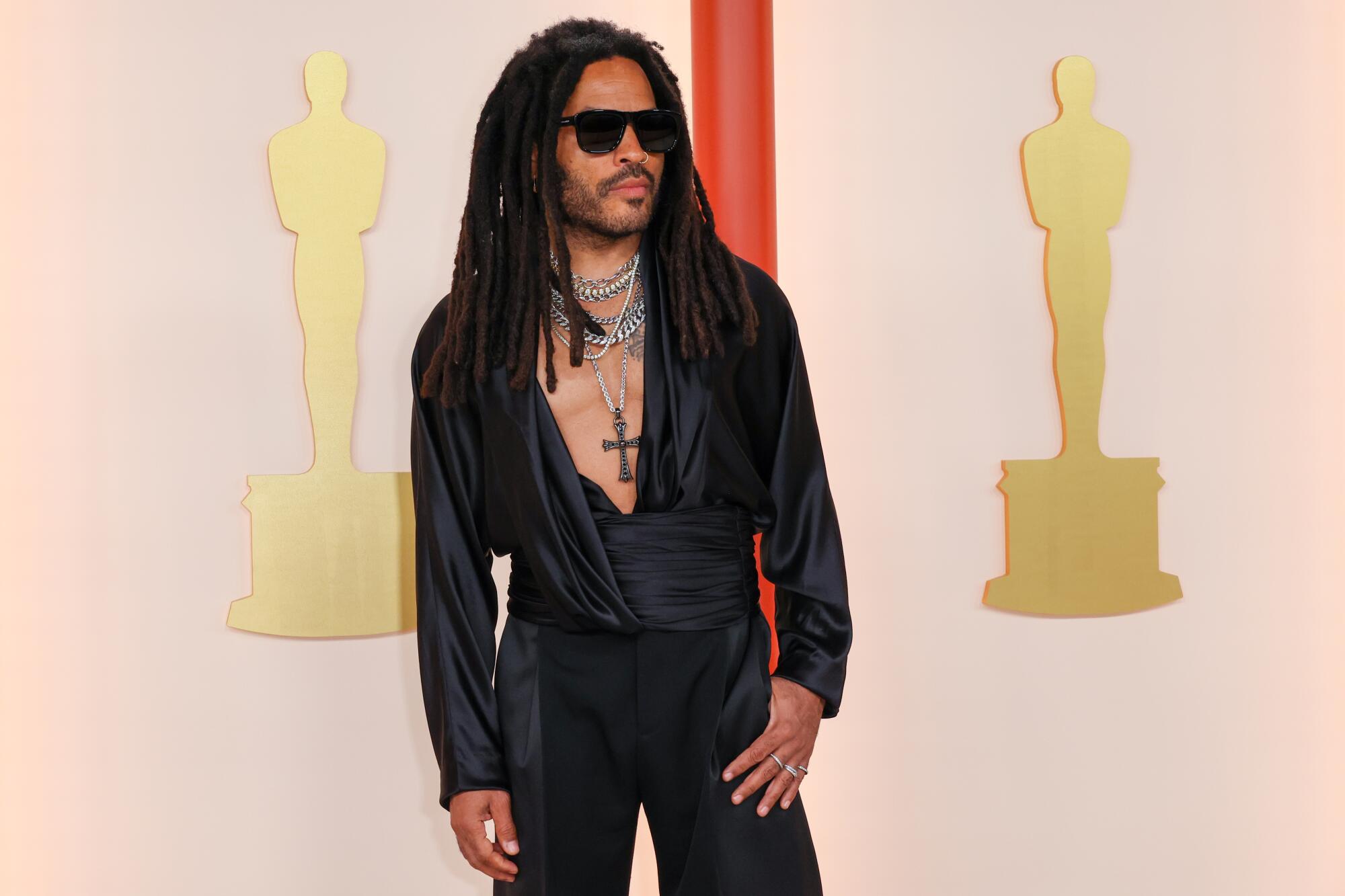 Lenny Kravitz in black tuxedo pants with dramatically draped black shirt. 