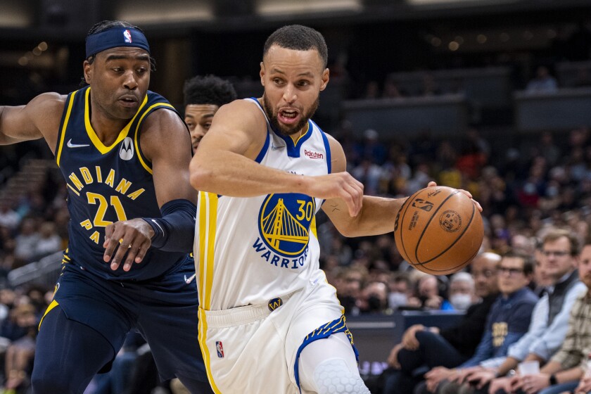Golden State Warriors guard Stephen Curry (30) drives the ball past the defense of Indiana Pacers guard Kelan Martin (21) during the first half of an NBA basketball game in Indianapolis, Monday, Dec. 13, 2021. (AP Photo/Doug McSchooler)