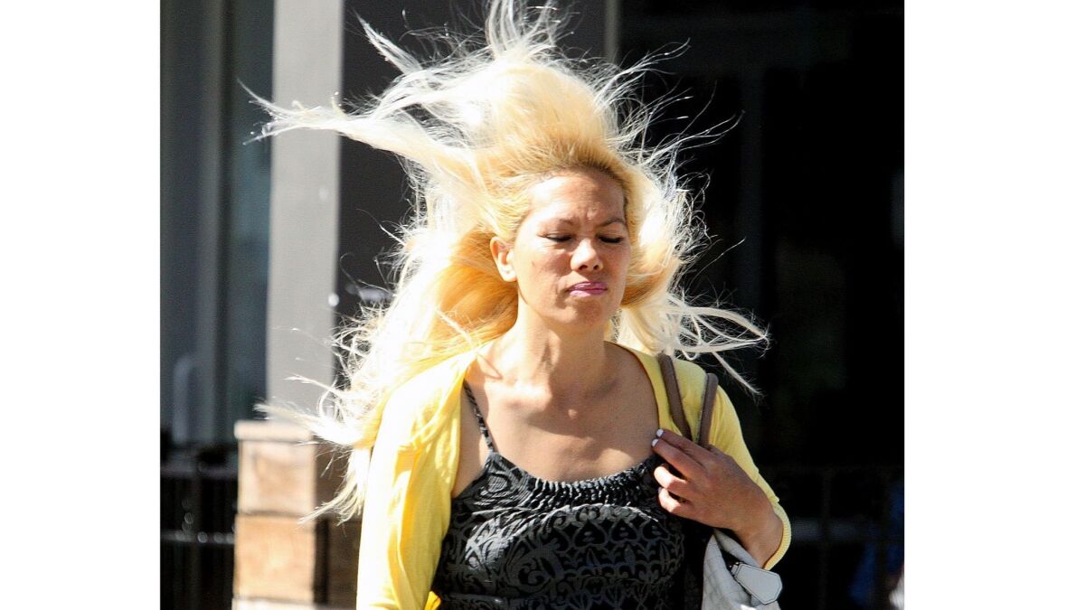 Jackie Sabaoan crosses the street on a windy day in Burbank. Gusts in the 30-to-50 mph range are expected in coastal and inland areas across Southern California on Monday and Tuesday.