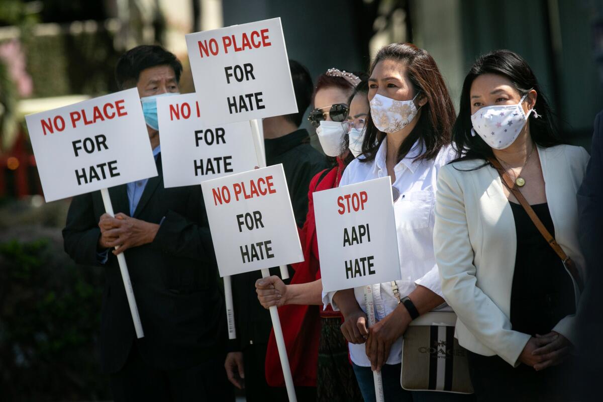 Community members hold signs calling for hate to stop