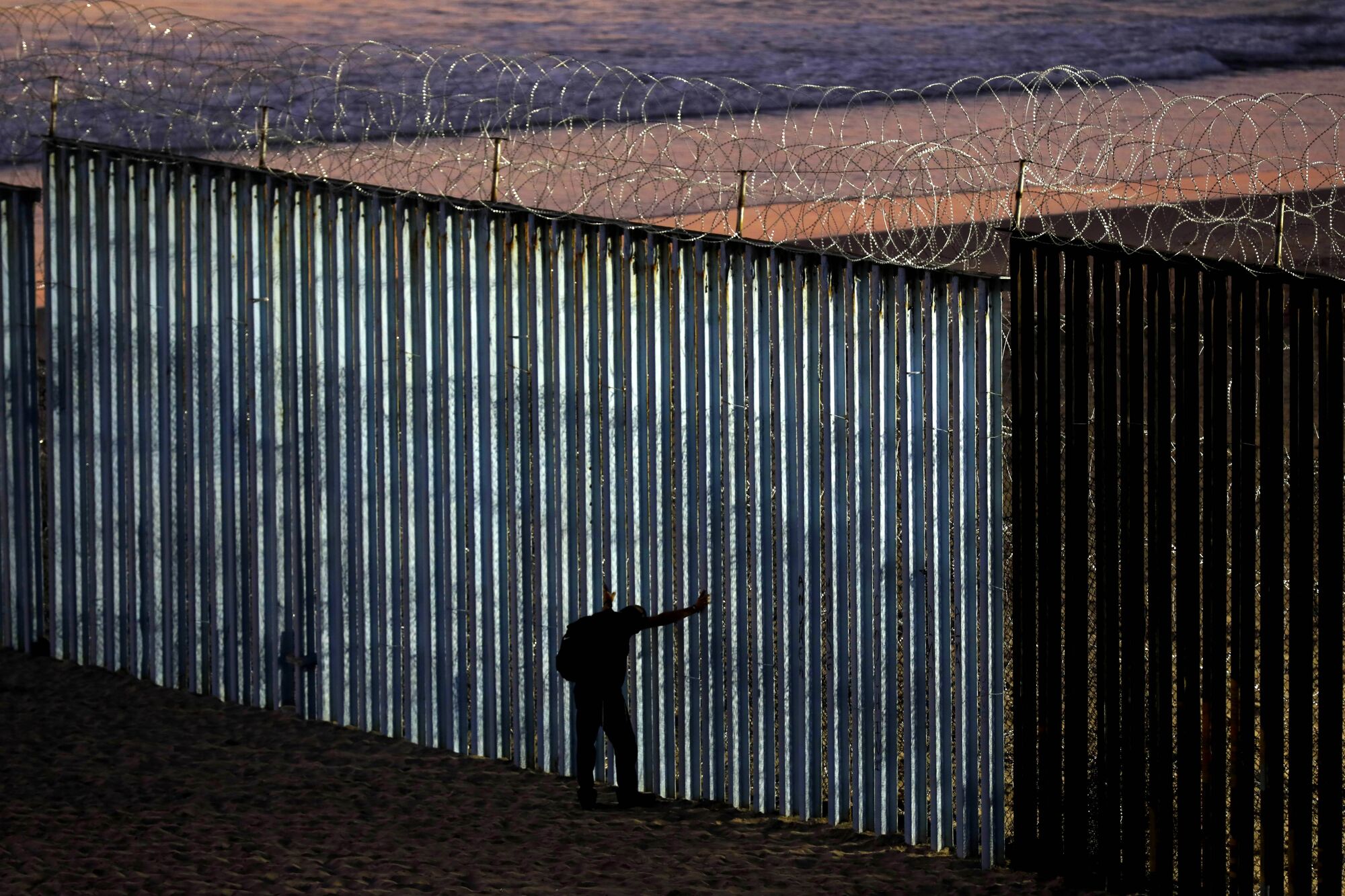A person leans against the U.S.-Mexico border wall in Tijuana.