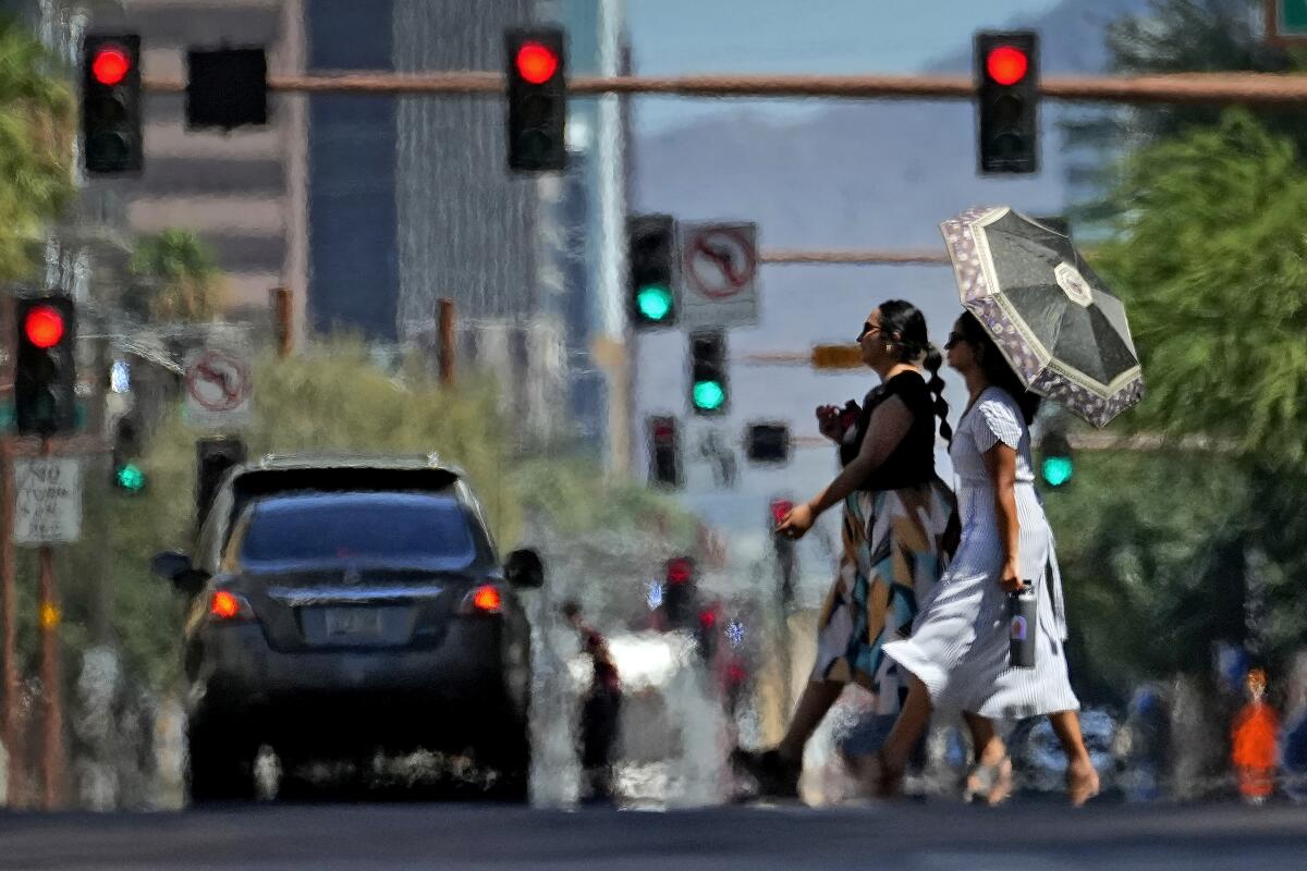 ARCHIVO- Ondas de calor envuelven a dos mujeres mientras cruzan la calle el 17 de julio de 2023,