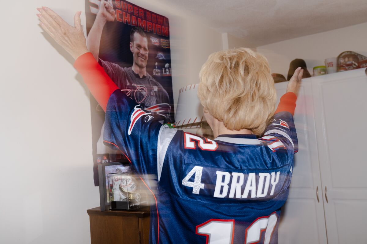 Cindy Adams celebrates in front of a Tom Brady poster.