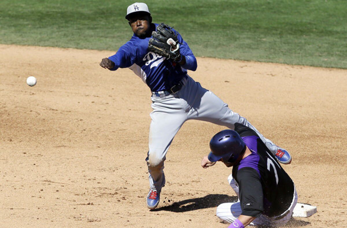 Dodgers shortstop Dee Gordon avoids Colorado's Kyle Parker on a throw to first base to complete a double play during an exhibition game this spring.