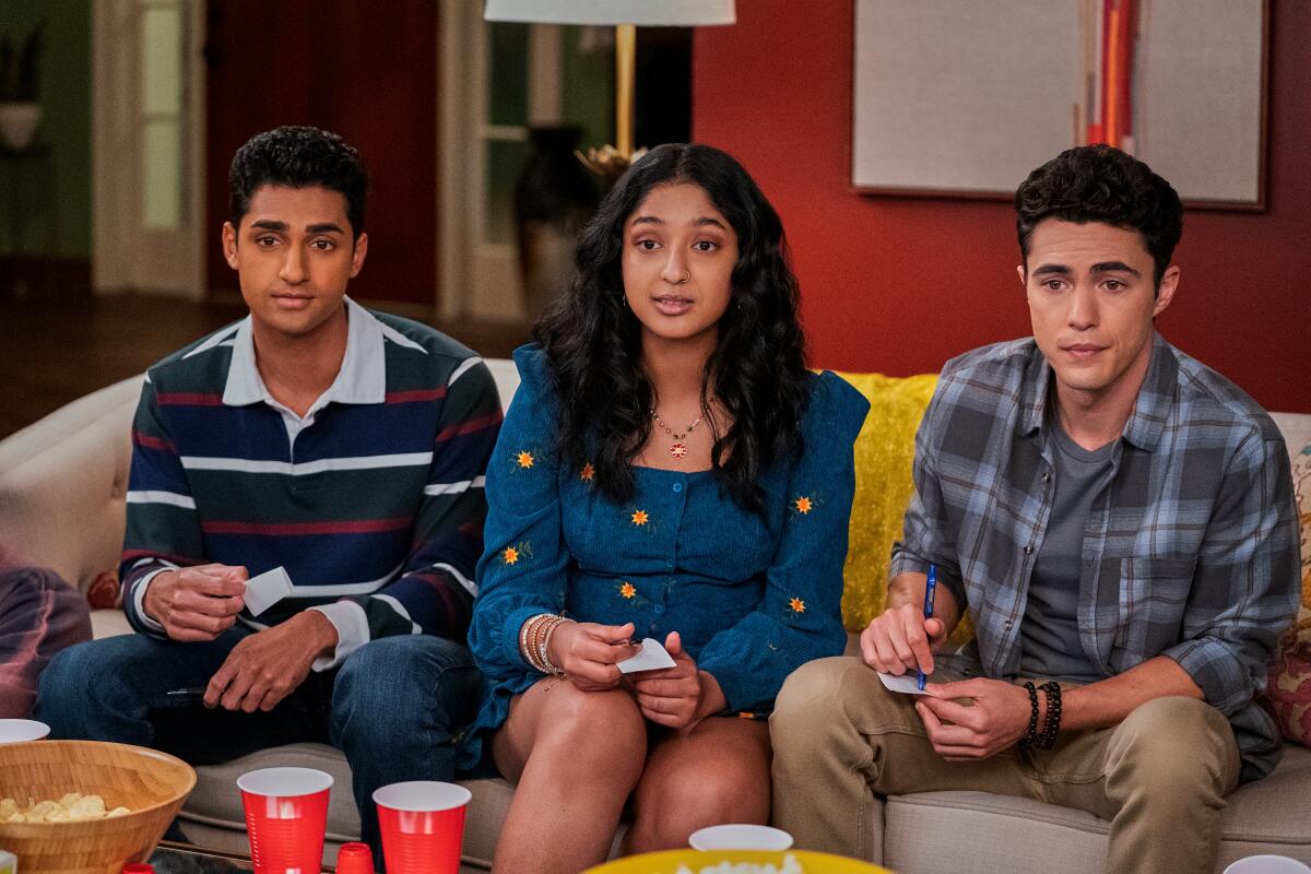 Three teenagers sitting together on a sofa during game night