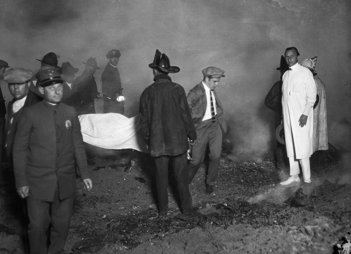 May 31, 1924: Rescue workers carry the remains of a victim of the fire at the Hope Development School.