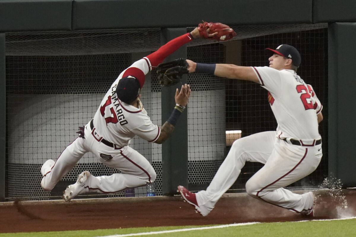 Atlanta Braves third baseman Johan Camargo catches a fly ball as Austin Riley looks on.
