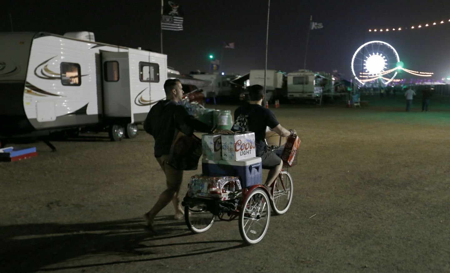 Two men arrive on a loaded tricycle full of beer and other drinks in the RV Resort for the 10th anniversary of the Stagecoach Country Music Festival at the Empire Polo Club in Indio.