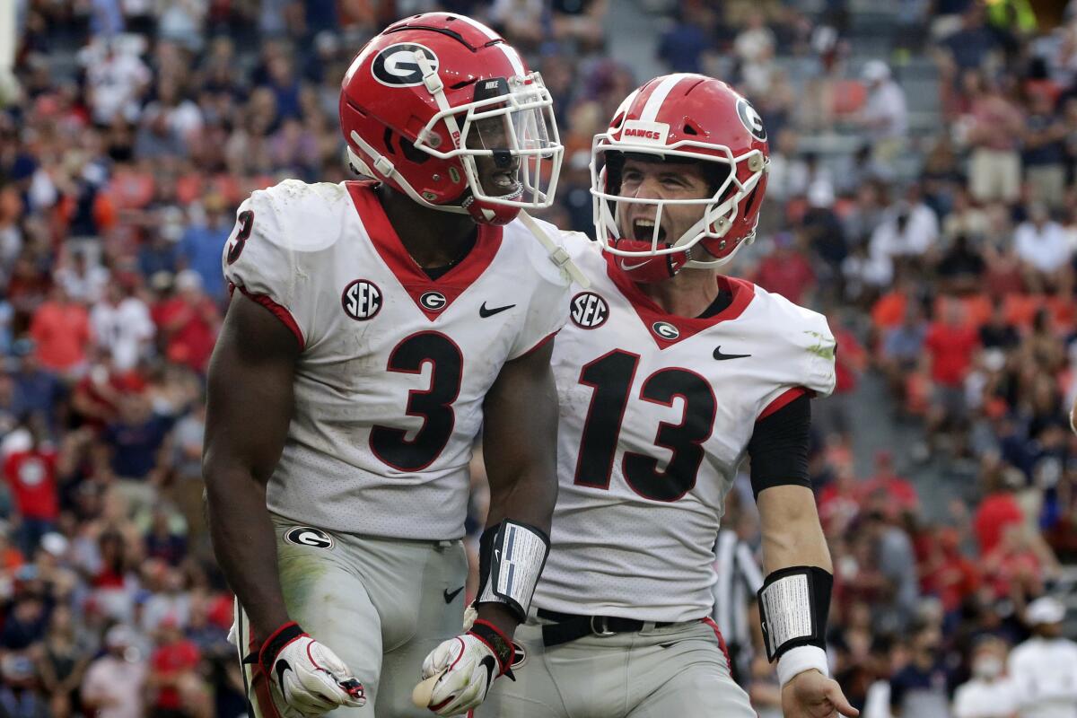 Georgia running back Zamir White (3) celebrates with quarterback Stetson Bennett (13) after scoring a touchdown against Auburn during the second half of an NCAA college football game Saturday, Oct 9, 2021 in Auburn, Al. (AP Photo/Butch Dill)