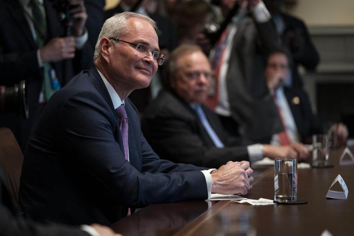 Exxon Mobil's Darren Woods sits at a table.