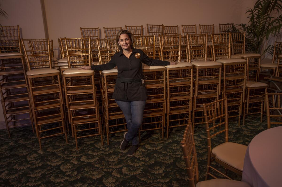 Ann Lancaster leans against rows of stacked chairs in a closed indoor-dining area of her restaurant.