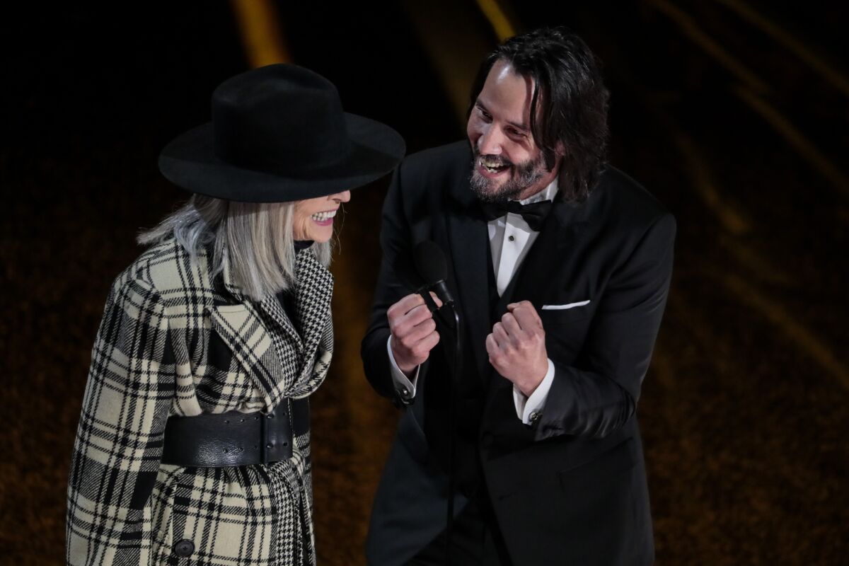 Keanu Reeves, in a tux, and Diane Keaton laugh onstage.