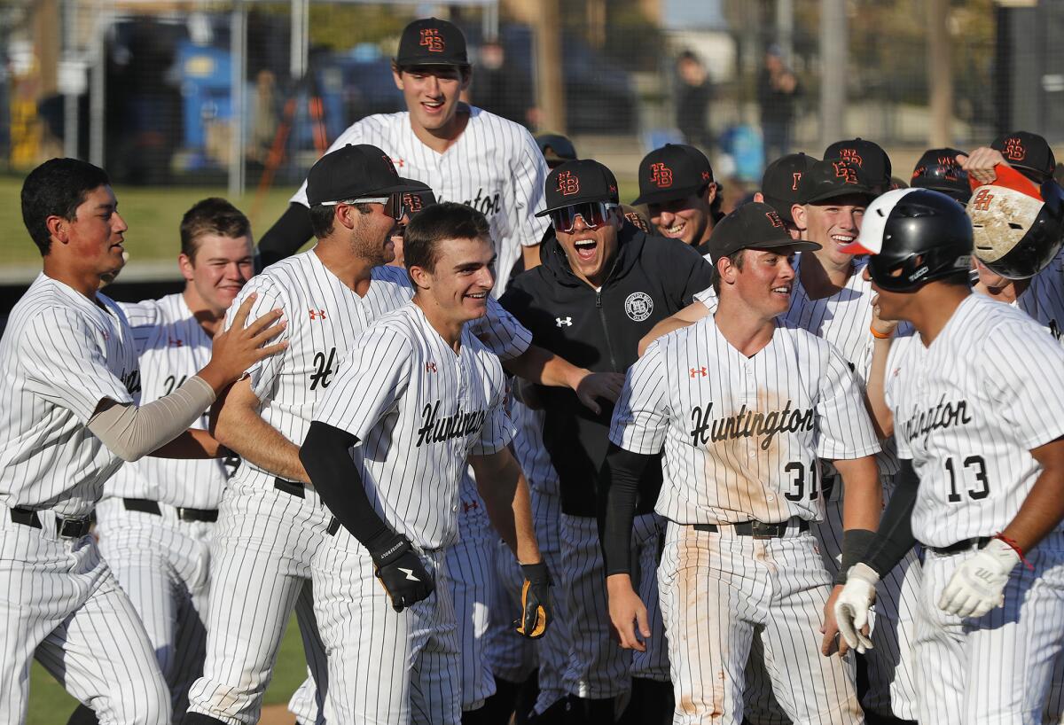 Huntington's Bradley Navarro, fourth from left, is mobbed by teammates after hitting a walk-off home run to defeat CdM.