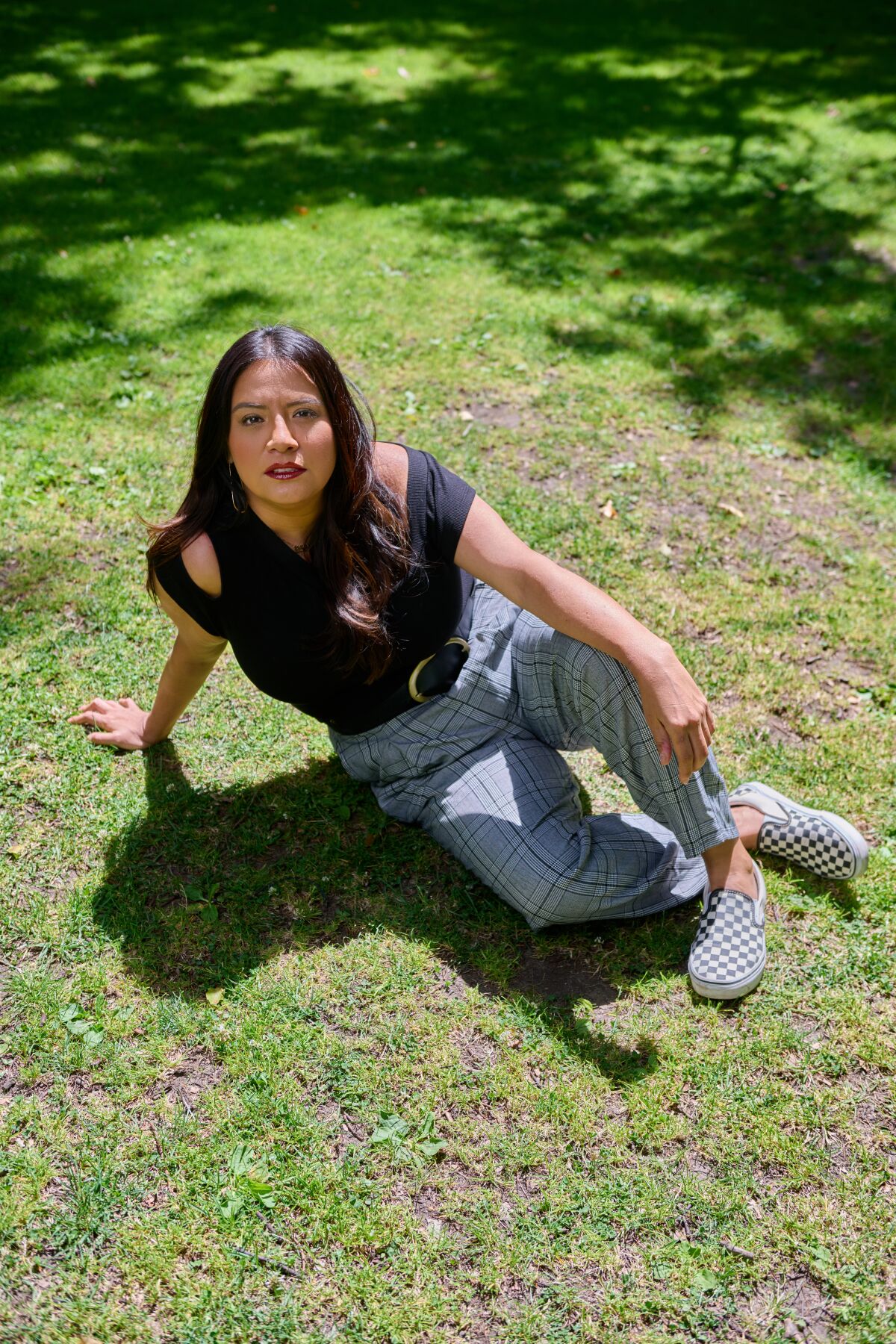 Comedian Cristela Alonzo sits on the grass at a park.