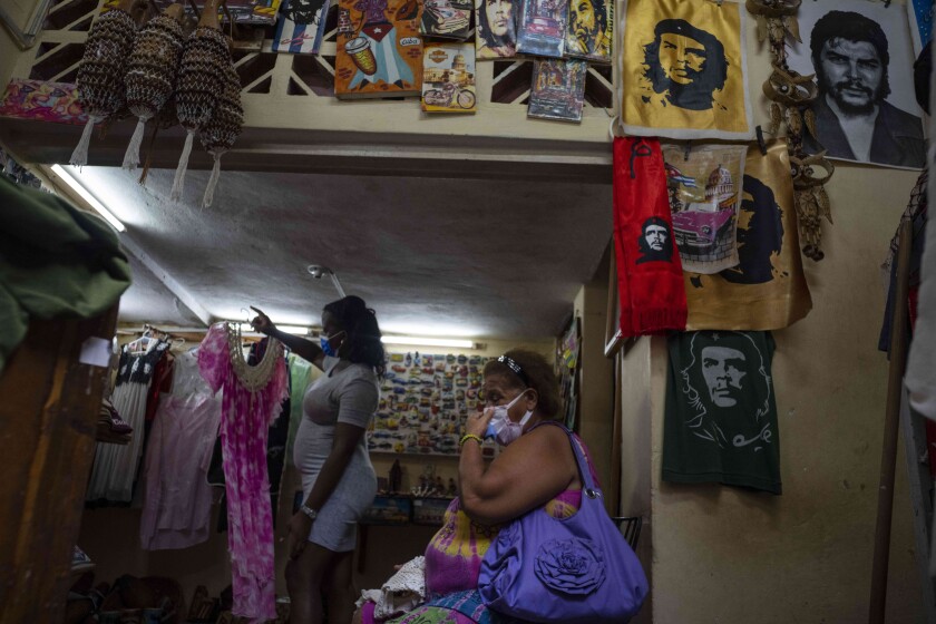 ARCHIVO - Una mujer espera que le muestren un vestido en una tienda privada de ropa y artesanías en La Habana, Cuba, el 16 de septiembre de 2021. En menos de tres meses de aplicación de un paquete de leyes que permite la apertura de pequeñas y medianas empresas en Cuba después de casi cinco décadas de prohibición, las autoridades aprobaron casi 900 de ellas, se anunció el jueves 2 de diciembre de 2021. (AP Foto/Ramón Espinosa, Archivo)