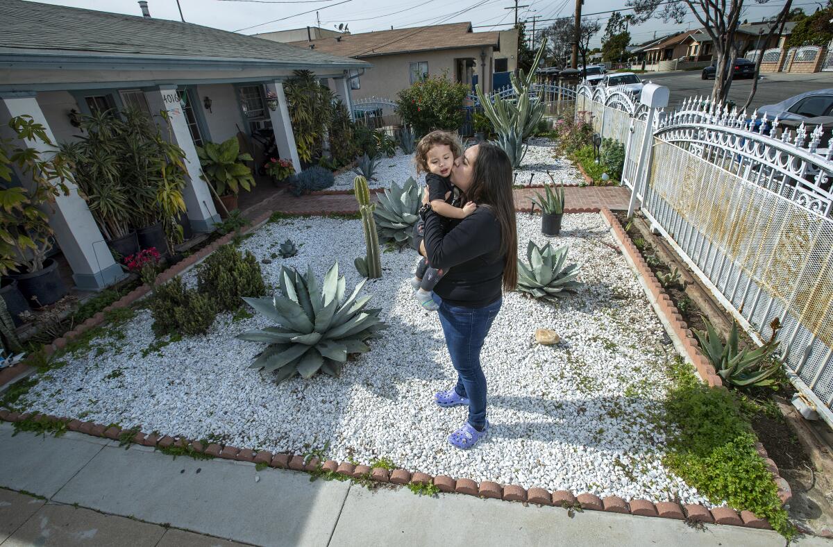Guadalupe Valdovinos holds her son, Thaddeus Diaz, in the front yard of their home in East Los Angeles. 