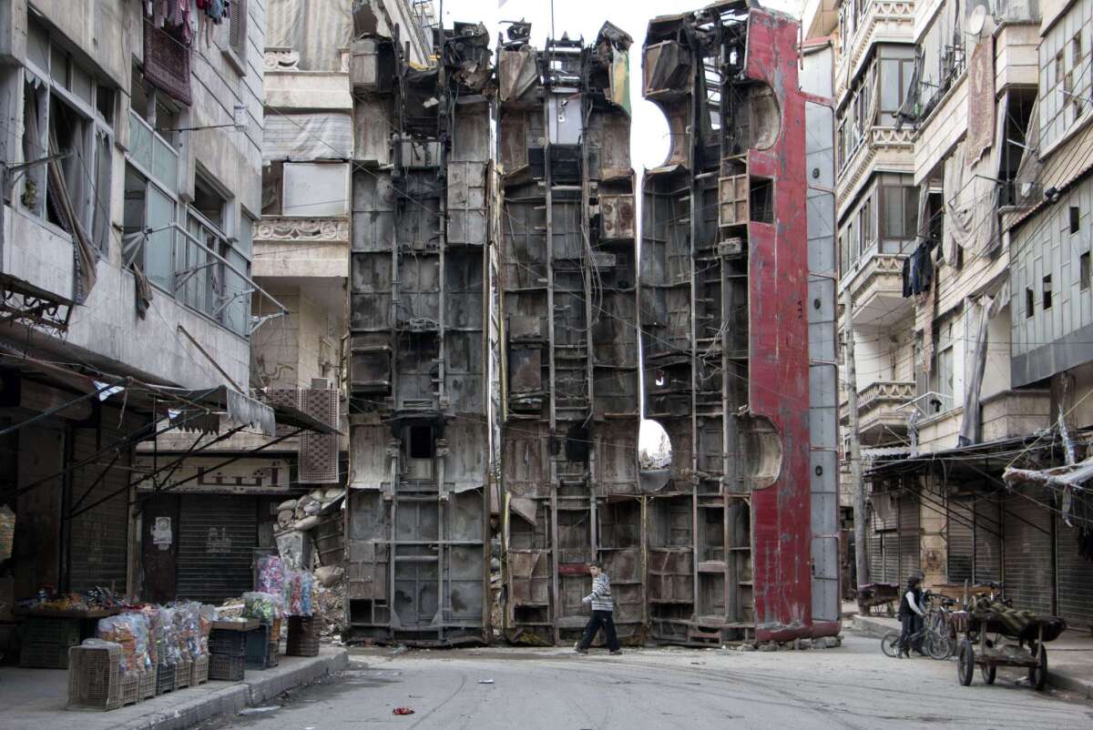 A boy walks past a makeshift barricade made of destroyed buses on the rebel-held side of Aleppo, Syria, on March 14.