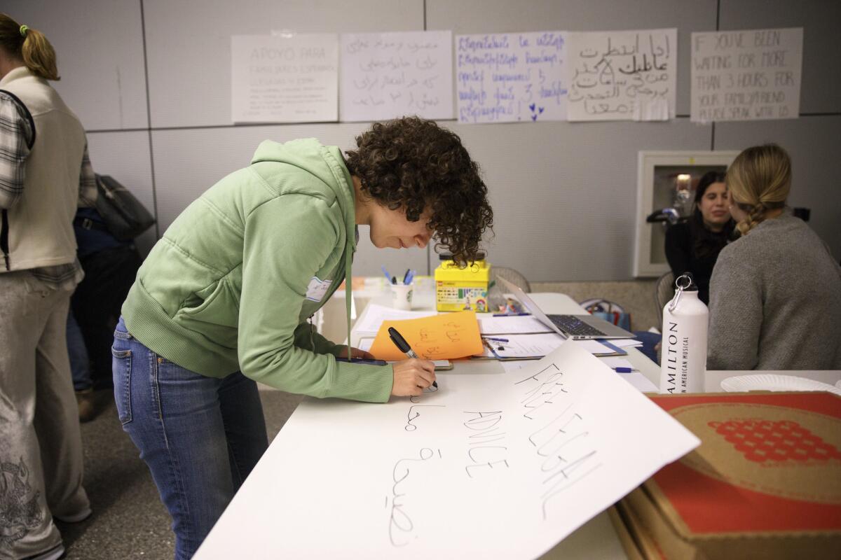 Volunteer Nour Joudah, a graduate student at UCLA, translates a sign into Arabic in the arrivals area of Tom Bradley International Terminal.