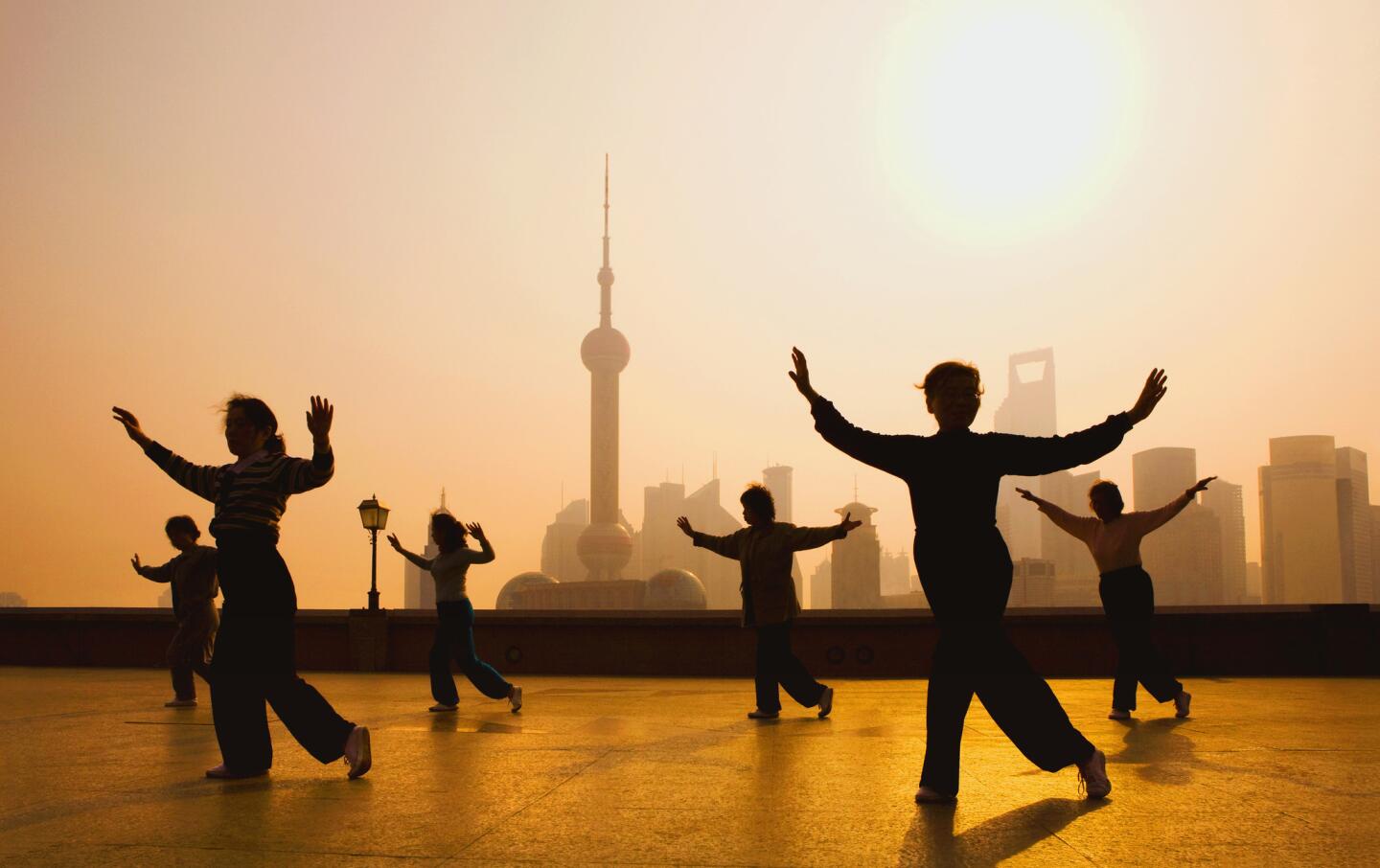 People gather to practice movements on the Bund, with the Shanghai skyline in the background.