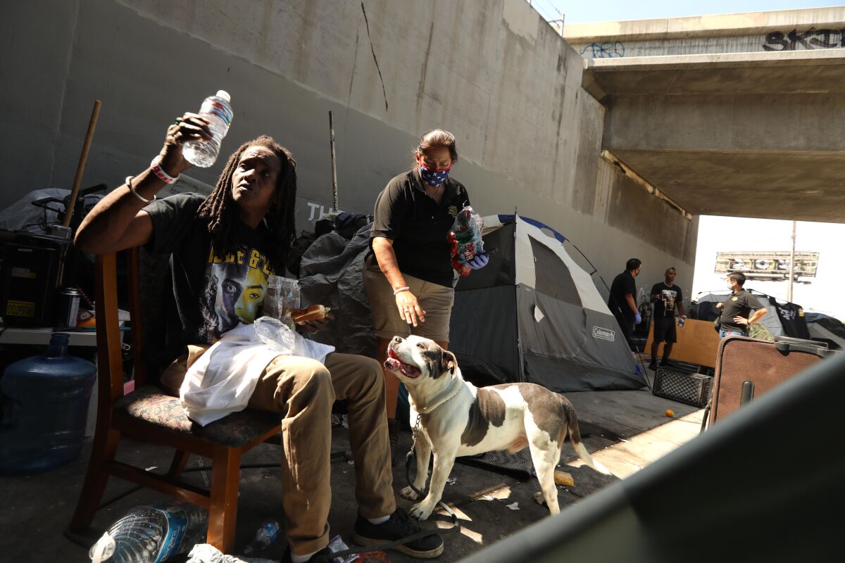 Outreach worker Monica Palma with Kim M., who is homeless, and her dog under the Santa Monica Freeway.