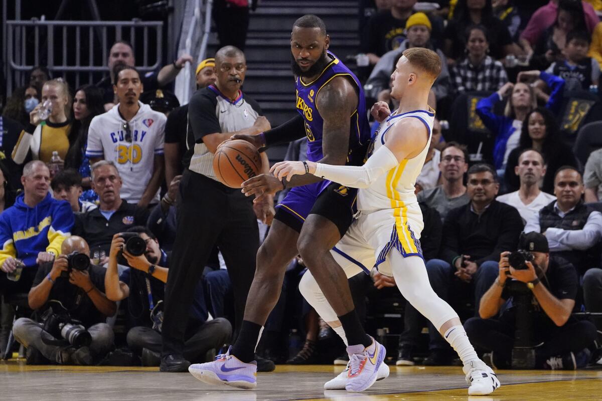 Golden State Warriors guard Donte DiVincenzo defends against Lakers forward LeBron James.