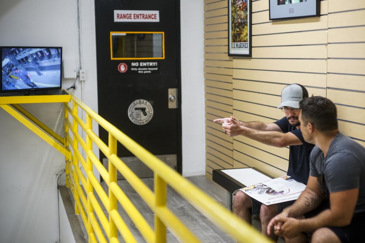 Marcus Axisa of Australia, left, gestures as if holding a firearm while talking with Oliver Girard of Canada while waiting for their turn in at the Waikiki Gun Club in Honolulu.