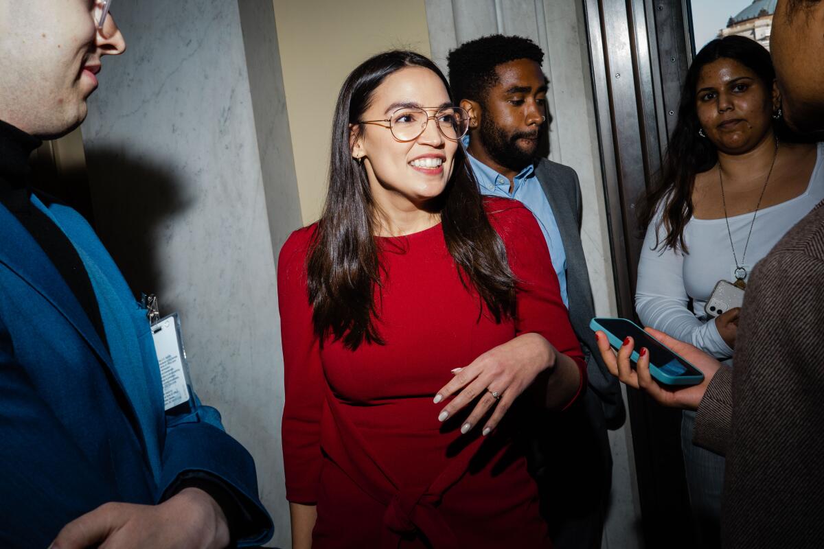 Alexandria Ocasio-Cortez standing as she speaks with a handful of people