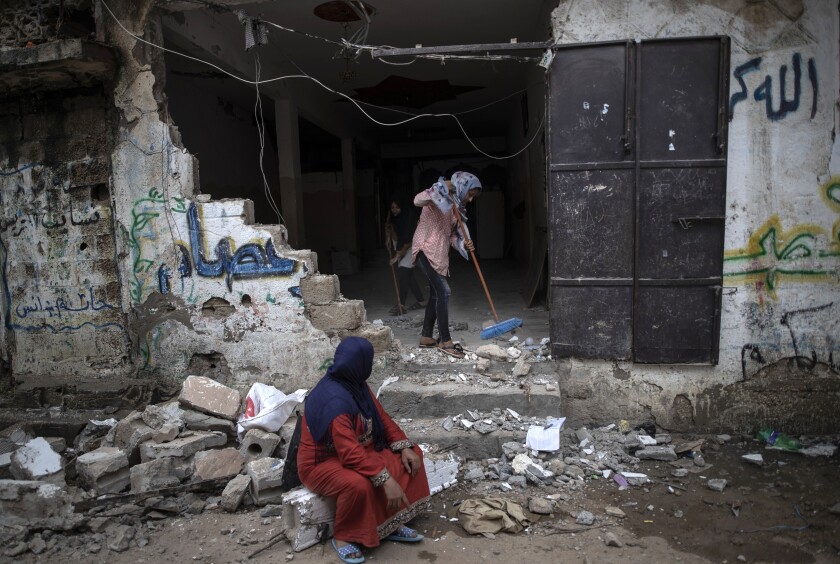 A Palestinian woman sweeps rubble from the ruins of her home Friday in the town of Beit Hanoun, northern Gaza Strip.
