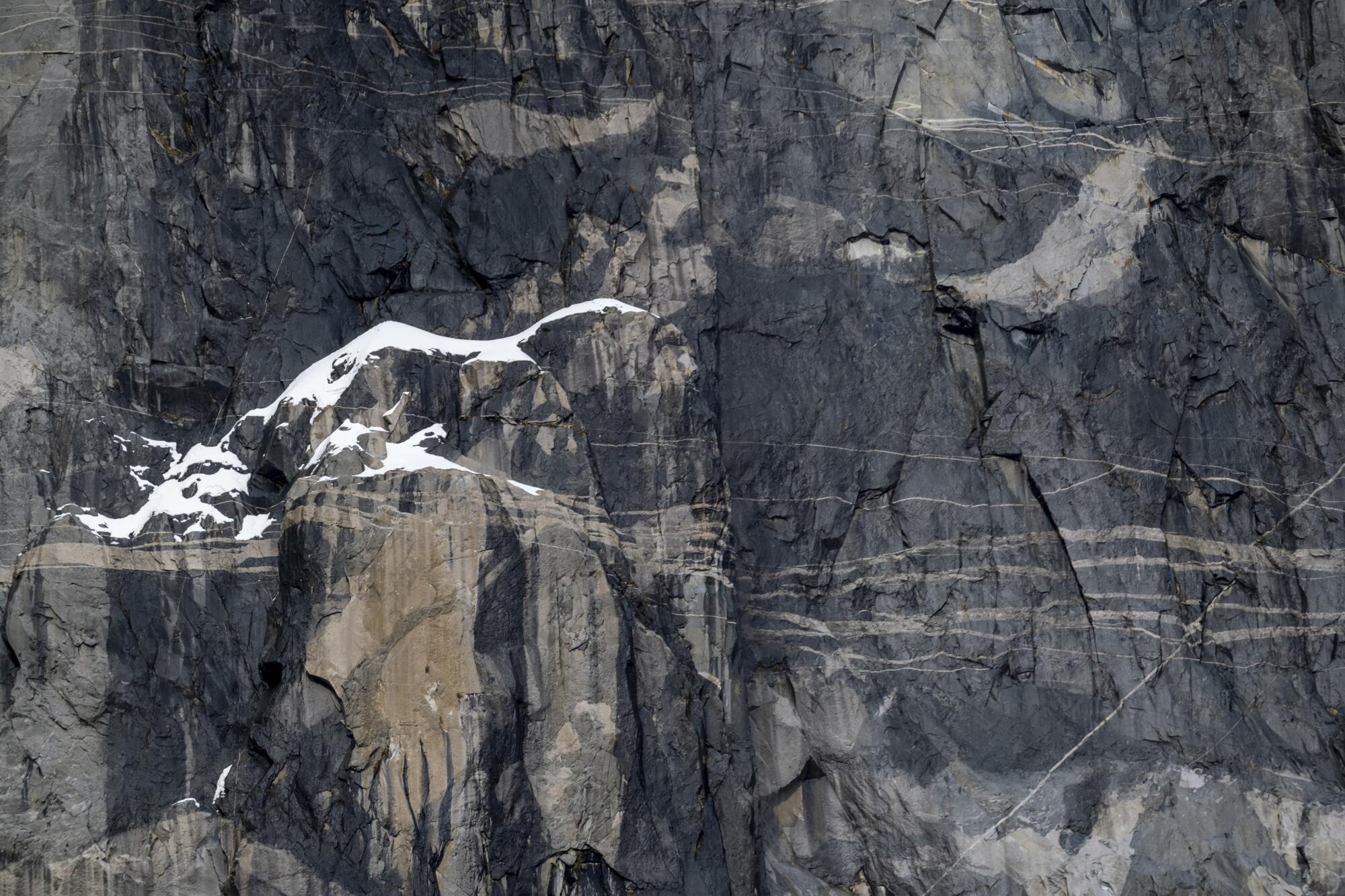 Snow clings to the steep granite rock walls of El Capitan.