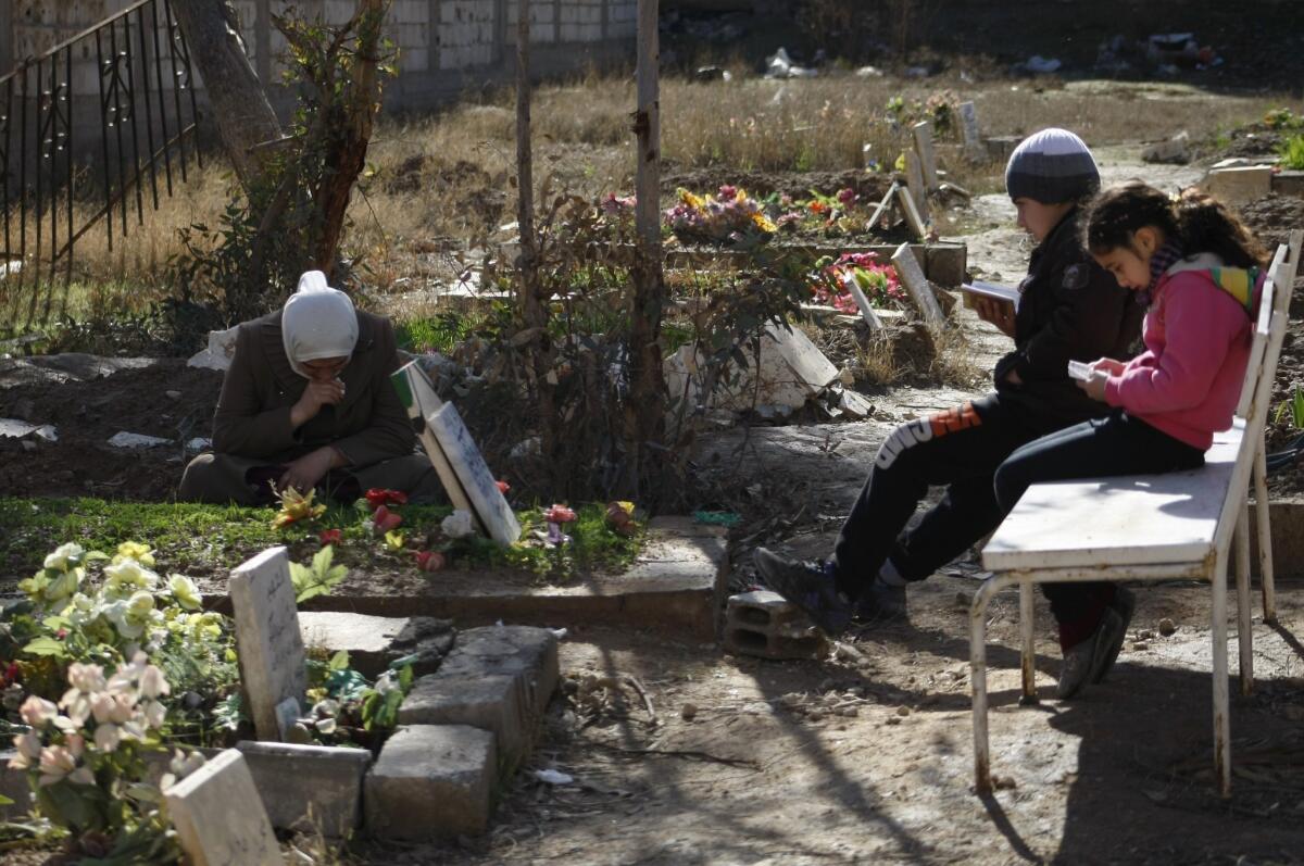 A Syrian woman mourns over the grave of her son, recently killed in fighting, in the northeastern city of Dair Alzour.