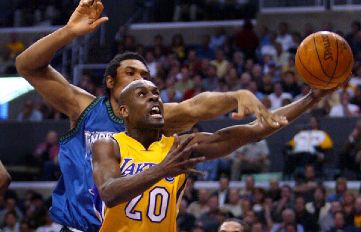 Lakers point guard Gary Payton scores on a driving layup against Minnesota Timberwolves center Michael Olowokandi.