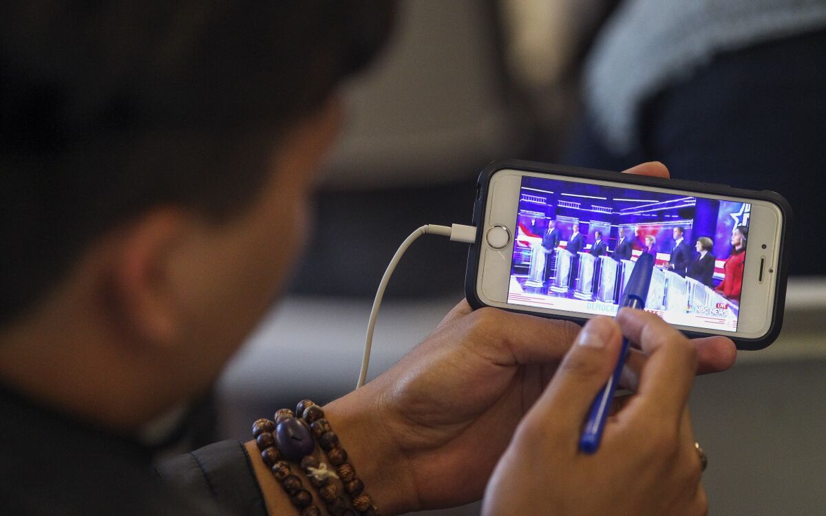 Ryan Roden, 19, a UCSD student, watches  the Democratic presidential debate on his phone during a watch party, put on by Youth Will, at the Jacobs Center For Neighborhood Innovation on Wednesday, June 26, 2019 in San Diego, California.