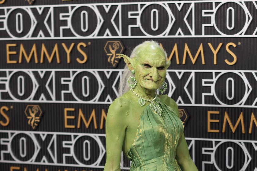 A person dressed as a green goblin wearing a green gown.  