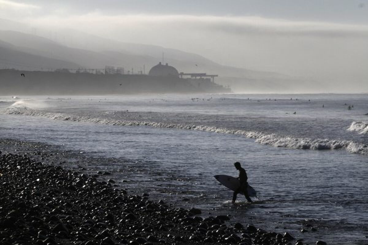 Early morning surfers catch a few waves with the San Onofre nuclear power plant in the background.