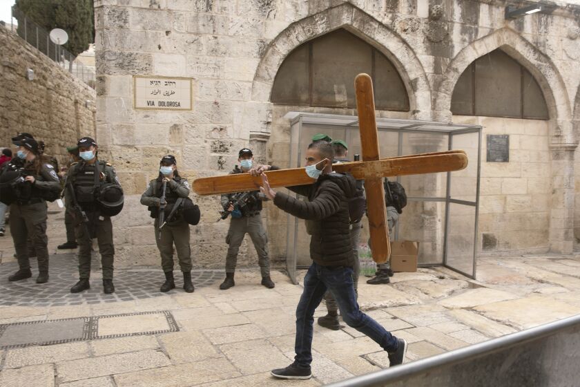 FILE - A Christian man carries a cross along the Via Dolorosa ahead of the Good Friday procession in Jerusalem's Old City, on April 2, 2021. Israeli police on Thursday, Feb. 2, 2023 arrested an American tourist after he allegedly knocked down and broke a statue of Jesus in a church in Jerusalem's Old City. Police said the man's mental health was being assessed. (AP Photo/Maya Alleruzzo)