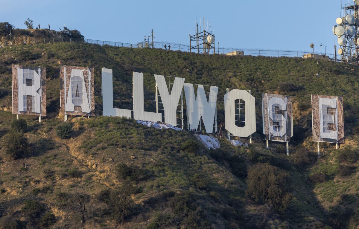Workers install letters to cover the Hollywood sign to eventually read 'RAMS HOUSE' Monday, Feb. 14, 2022 in Hollywood, CA.