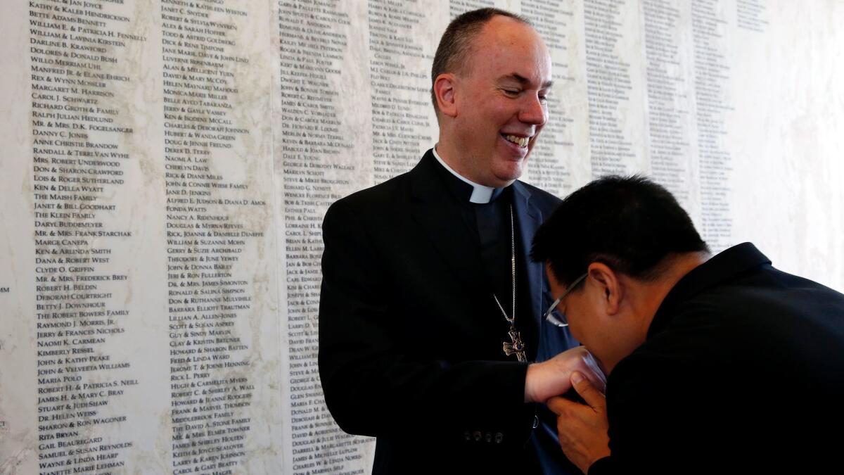 Father Thomas Naval, right, of Santiago de Compostela Catholic Church in Lake Forest, leans in to congratulate Rev. Timothy Freyer after he was named auxiliary bishop for the Diocese of Orange.