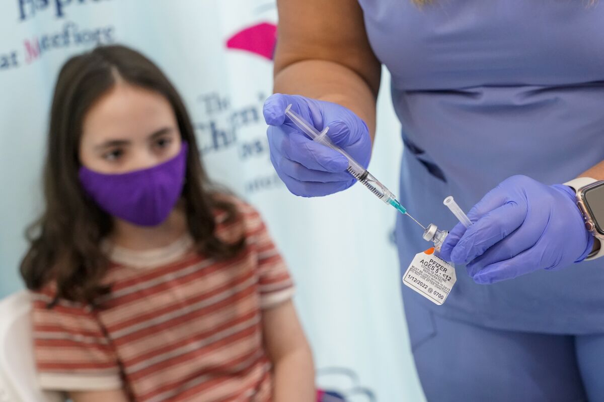 FILE - Jamie Onofrio Franceschini, 11, watches as RN Rosemary Lantigua prepares a syringe with her first dose of the Pfizer COVID-19 vaccine for children five to 12 years at The Children's Hospital at Montefiore, Nov. 3, 2021, in the Bronx borough of New York. The United States is steadily chipping away at vaccine hesitancy and driving down COVID-19 cases and hospitalizations to the point that schools, governments and corporations are lifting mask restrictions yet again. (AP Photo/Mary Altaffer, File)