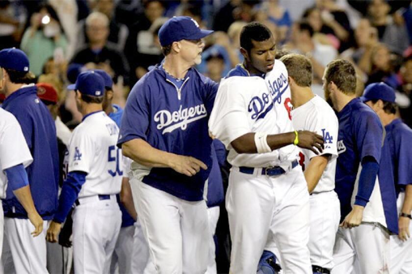 Dodgers hitting coach Mark McGwire escorts right fielder Yasiel Puig away from the fighting after a bench-clearing brawl erupted after pitcher Zack Greinke was hit by a pitch in the seventh inning on Tuesday.