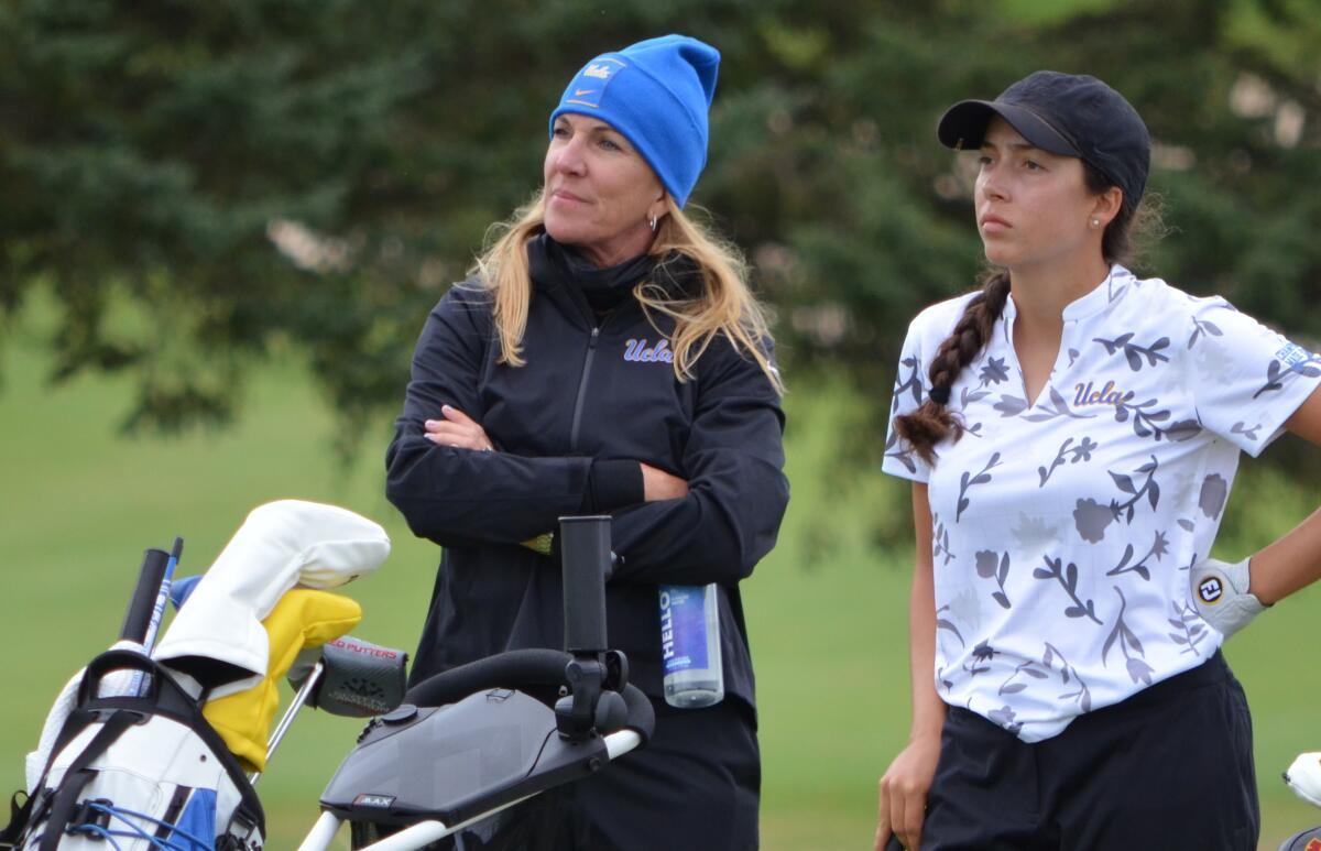 Carrie Forsyth, outgoing UCLA women's golf coach, stands with a person on a golf course