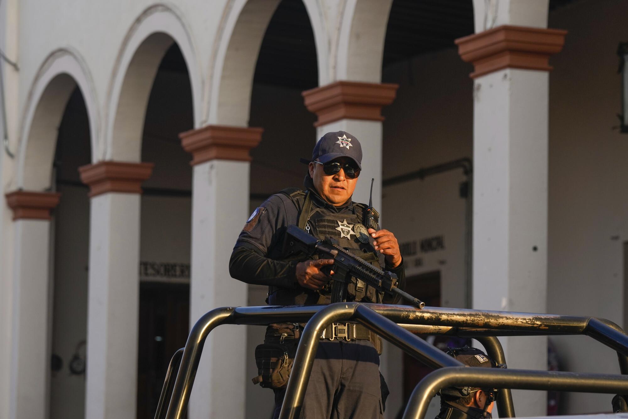 A man in uniform with a long rifle guards a building in Mexico's Michoacan state