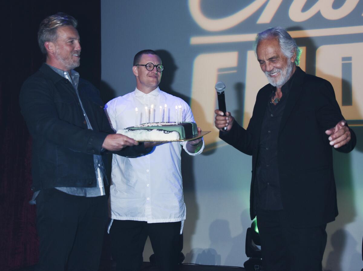 Paris Chong, left, and Guy Logan present a birthday cake to Tommy Chong, far right, at a May 24 party at Mack Sennett Studios in Silver Lake that doubled as a launch of the Chong's Choice cannabis line.