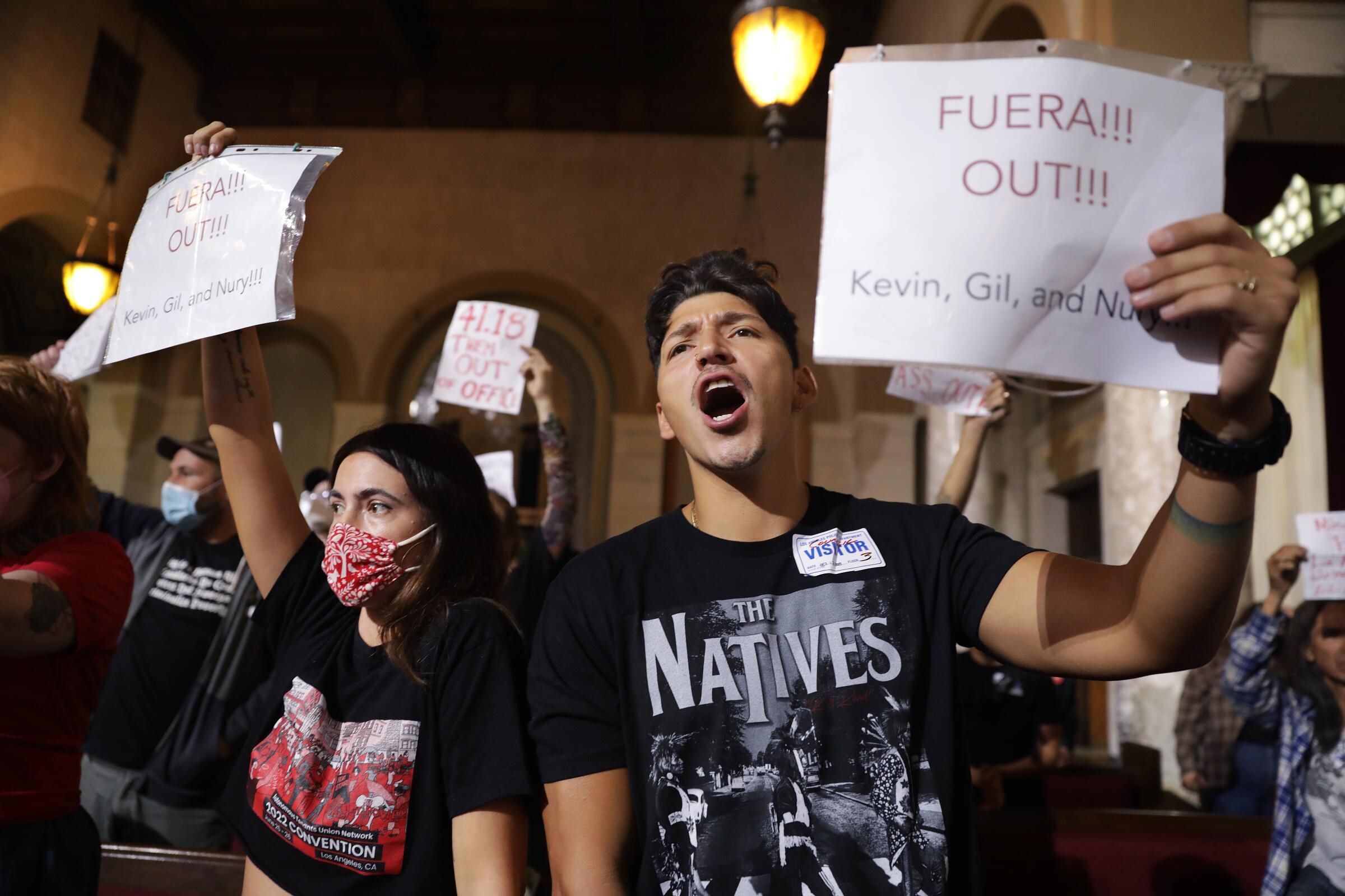 Protesters hold signs reading "Fuera!!! Out!!!" at Los Angeles City Hall on Tuesday. 