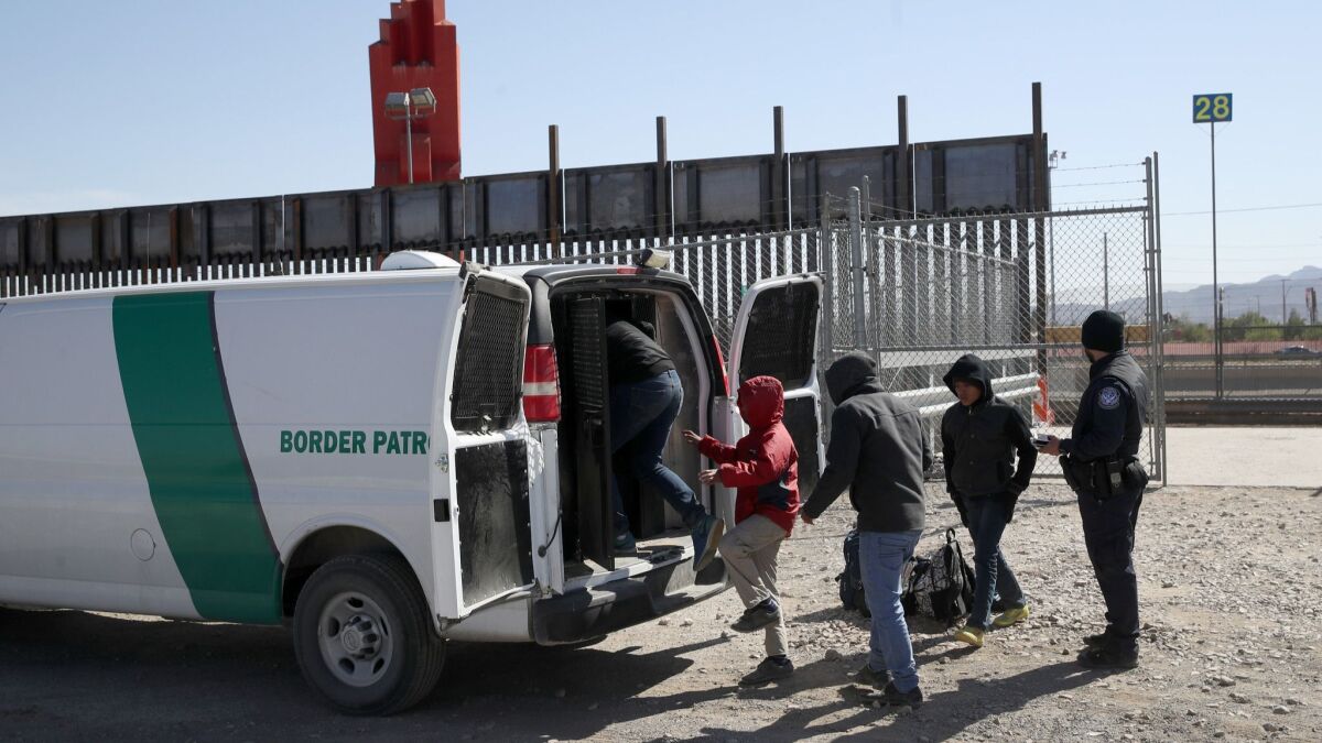 A U.S. Border Patrol agent loads detained migrants into a van at the border in El Paso, Texas.