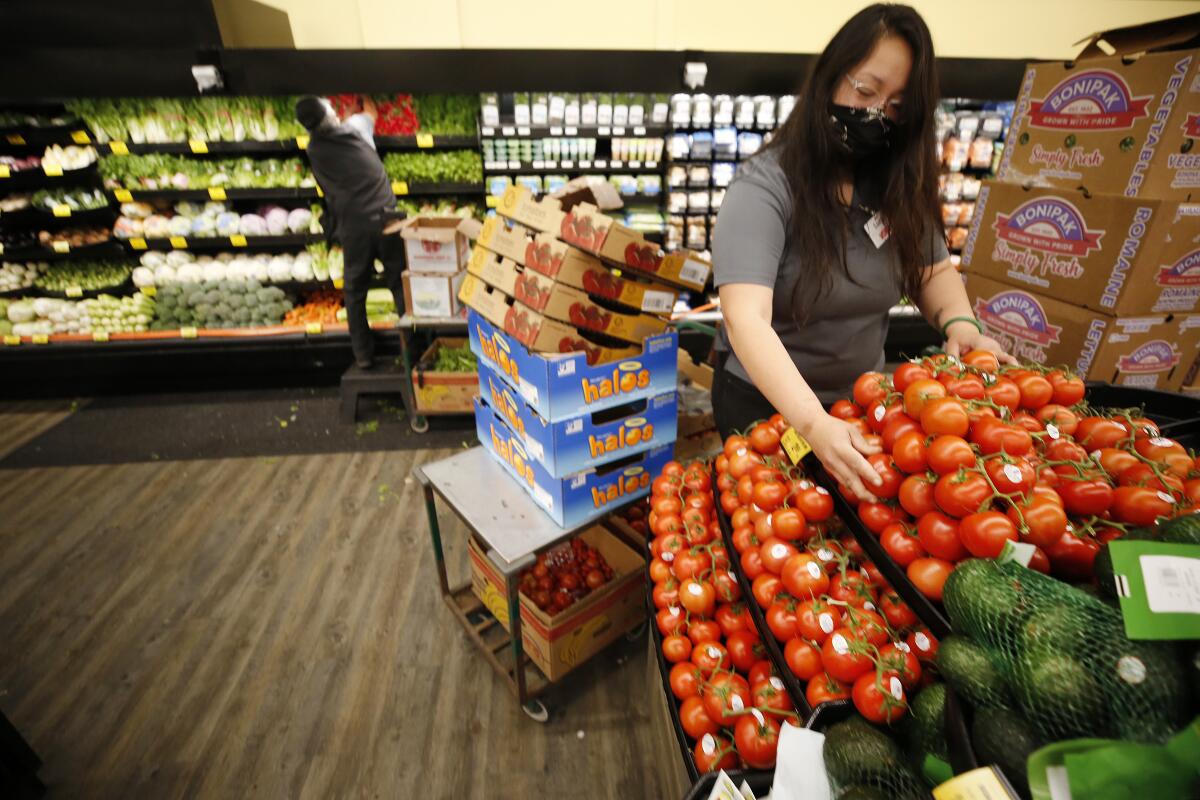 Two people work in the produce section of a market.