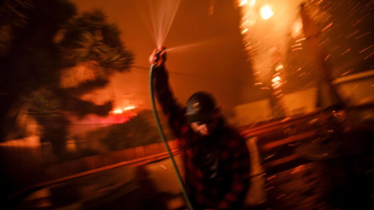 Prescott McKenzie hoses down the roof as embers move with the wind.