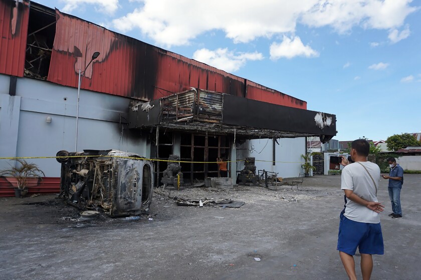 Un hombre observa los restos calcinados de un club nocturno que se incendio después de que dos grupos se enfrenaron dentro del lugar, el martes 25 de enero de 2022, en la ciudad de Sorong, en la provincia de Papúa Occidental, Indonesia. (AP Foto)